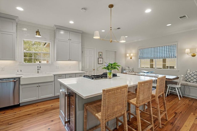 kitchen with sink, hanging light fixtures, a kitchen island, stainless steel appliances, and a kitchen bar