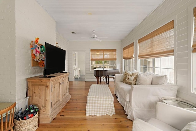 living room with ceiling fan, brick wall, and light hardwood / wood-style floors