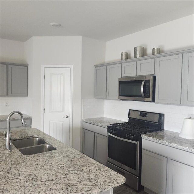 5574 Grand Springs Rd, Slidell, LA 70461 - kitchen with stainless steel appliances, a sink, gray cabinets, and decorative backsplash