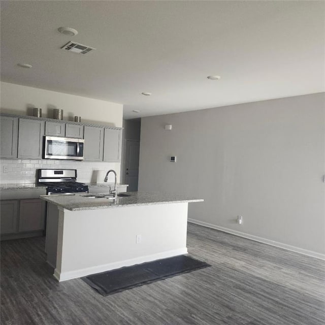 5574 Grand Springs Rd, Slidell, LA 70461 - kitchen with stainless steel appliances, a sink, dark wood-style floors, backsplash, and an island with sink