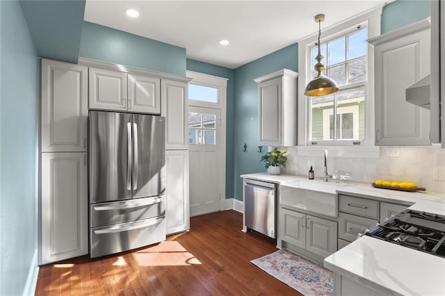 kitchen with pendant lighting, sink, appliances with stainless steel finishes, backsplash, and light stone counters