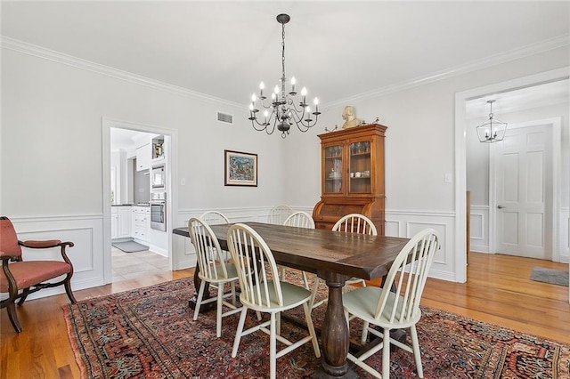 dining room featuring an inviting chandelier, ornamental molding, and light hardwood / wood-style floors