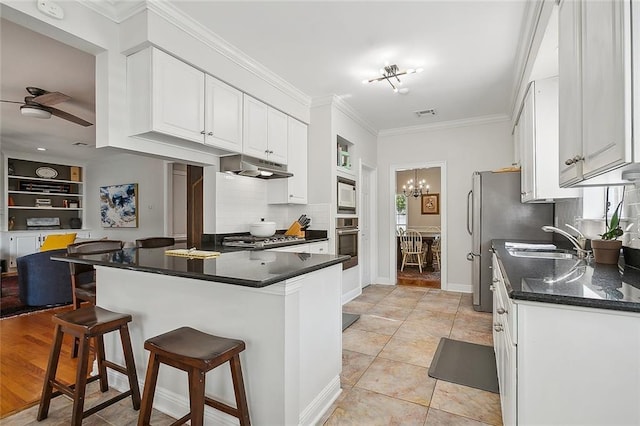 kitchen featuring sink, a breakfast bar area, appliances with stainless steel finishes, kitchen peninsula, and white cabinets