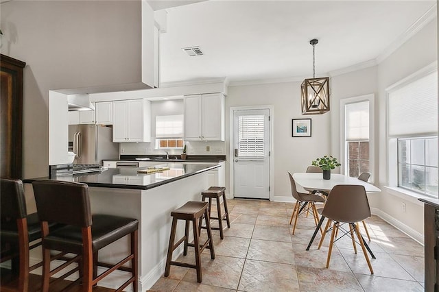 kitchen featuring crown molding, stainless steel fridge, a breakfast bar, white cabinetry, and decorative light fixtures