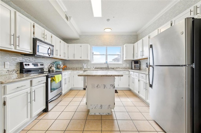 kitchen with light tile patterned flooring, a kitchen island, white cabinets, ornamental molding, and stainless steel appliances