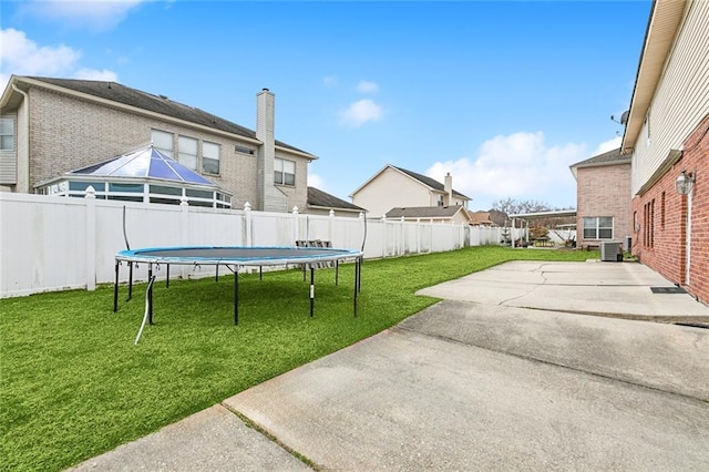 view of yard with a trampoline, central AC unit, and a patio