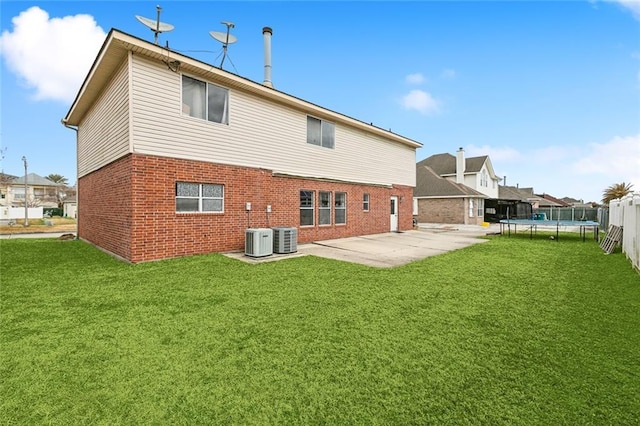 back of house with a trampoline, a yard, and a patio