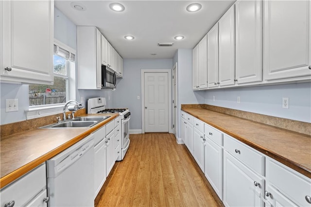 kitchen with light wood-type flooring, white appliances, sink, and white cabinets