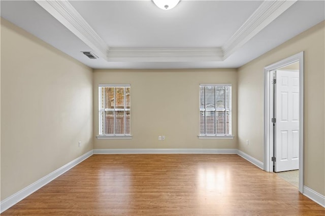 unfurnished room with a tray ceiling, ornamental molding, and light hardwood / wood-style floors