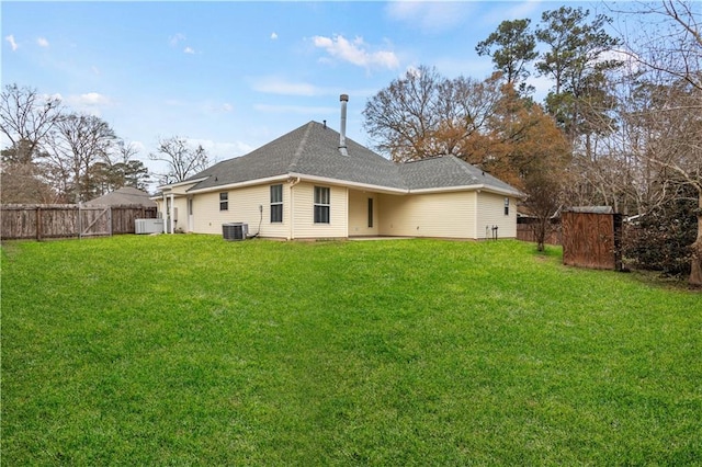 rear view of house featuring central AC unit and a lawn