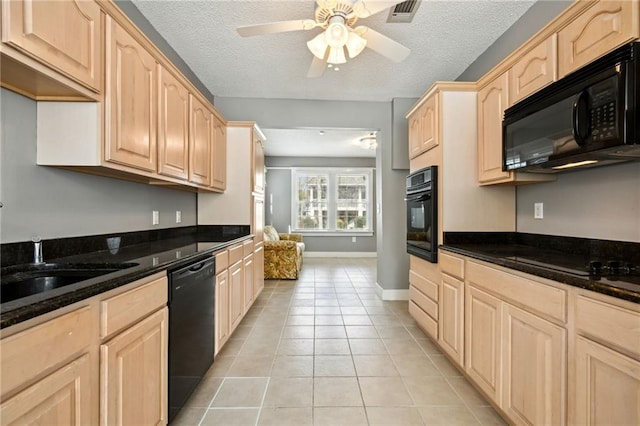 kitchen featuring light tile patterned flooring, dark stone countertops, black appliances, light brown cabinets, and a textured ceiling