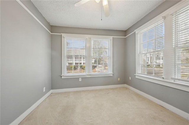 carpeted spare room with ceiling fan, a textured ceiling, and a wealth of natural light