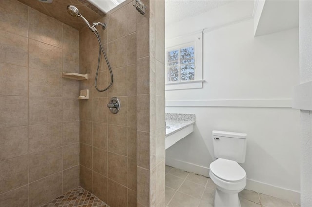 bathroom featuring tile patterned flooring, vanity, a tile shower, and toilet