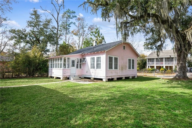 back of property featuring a sunroom and a lawn