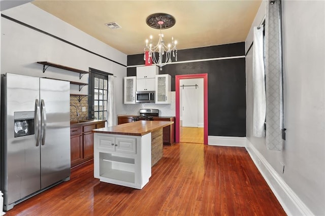 kitchen featuring dark hardwood / wood-style floors, wooden counters, decorative backsplash, hanging light fixtures, and stainless steel appliances