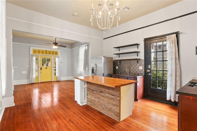 kitchen with wood-type flooring, decorative backsplash, butcher block countertops, and stainless steel fridge with ice dispenser