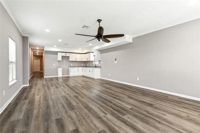 unfurnished living room with dark hardwood / wood-style flooring, sink, crown molding, and ceiling fan