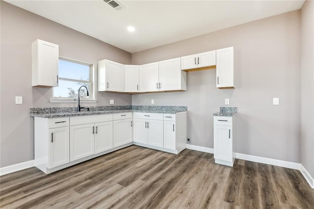 kitchen featuring light stone counters, dark wood-type flooring, sink, and white cabinets