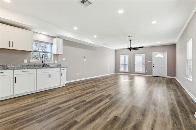 unfurnished living room featuring crown molding, ceiling fan, dark hardwood / wood-style floors, and sink