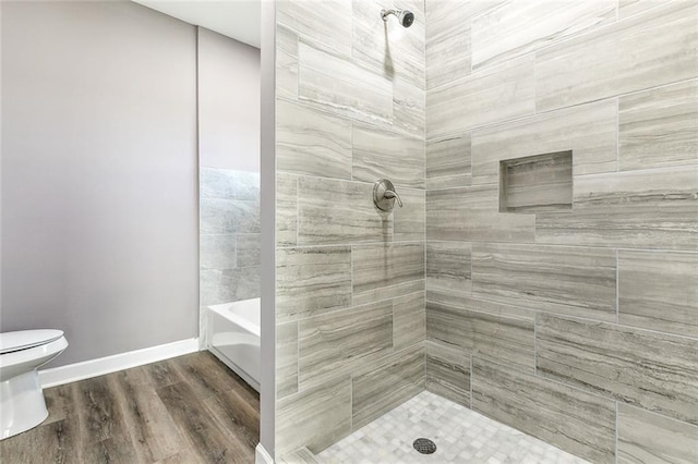 bathroom with a tile shower, hardwood / wood-style floors, and toilet