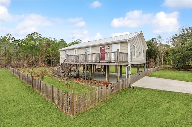 back of property with a wooden deck, a carport, and a yard