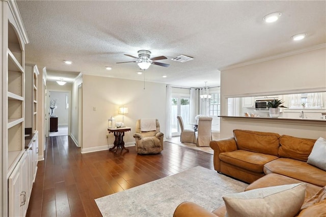 living room featuring ornamental molding, ceiling fan with notable chandelier, a textured ceiling, and dark hardwood / wood-style flooring