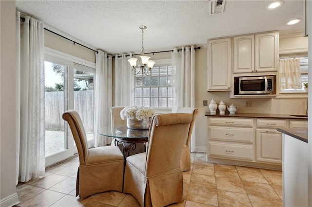 tiled dining space with a notable chandelier and a textured ceiling