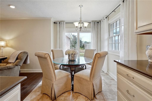 dining space featuring ornamental molding, a chandelier, a textured ceiling, and light wood-type flooring