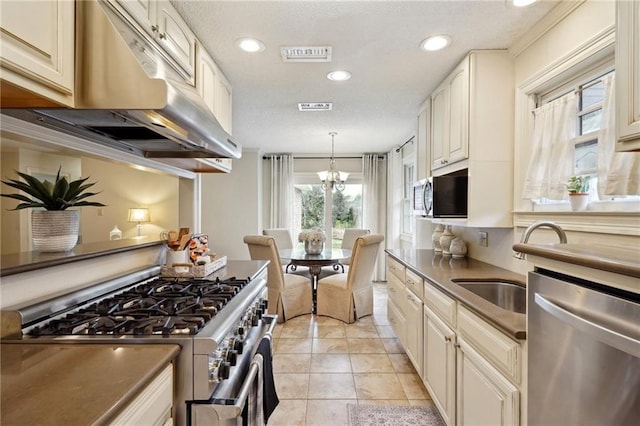 kitchen with sink, hanging light fixtures, light tile patterned floors, stainless steel appliances, and an inviting chandelier