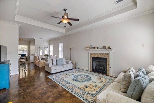 living room with ceiling fan, ornamental molding, a raised ceiling, and a tile fireplace