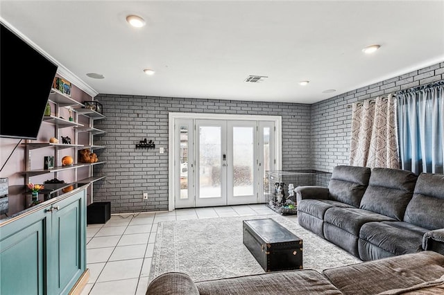 living room featuring light tile patterned flooring, brick wall, and french doors