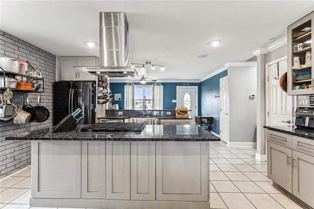 kitchen featuring black refrigerator, light tile patterned floors, sink, and dark stone counters