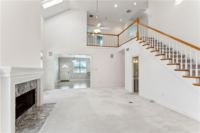 unfurnished living room with a high end fireplace, carpet floors, ceiling fan, and a high ceiling