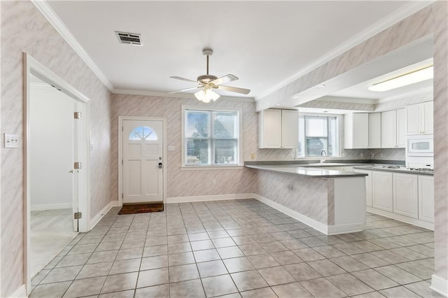 kitchen with white cabinetry, crown molding, white microwave, and kitchen peninsula