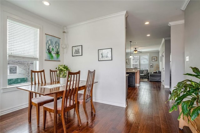 dining room featuring ornamental molding, dark wood-type flooring, a wealth of natural light, and ceiling fan