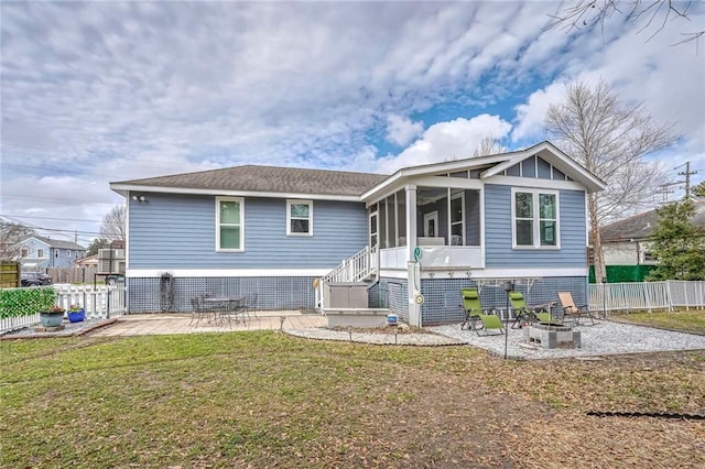 back of house featuring a patio, a sunroom, a yard, and a fire pit