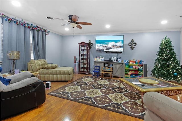 living room with hardwood / wood-style floors, ornamental molding, and ceiling fan