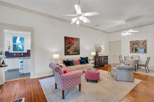 living room featuring hardwood / wood-style flooring, crown molding, and ceiling fan