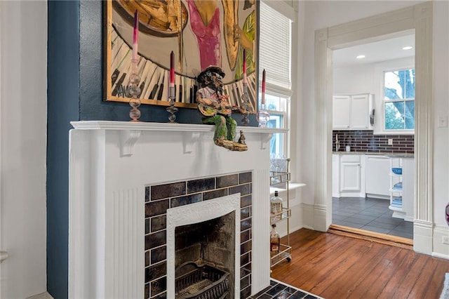 room details featuring hardwood / wood-style floors, a tile fireplace, and backsplash