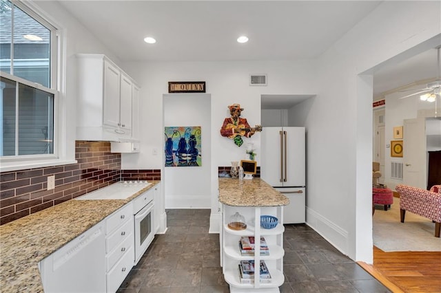 kitchen featuring white cabinetry, decorative backsplash, ceiling fan, light stone countertops, and white appliances