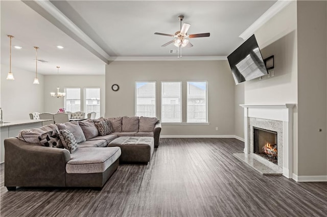 living room with dark hardwood / wood-style flooring, ornamental molding, ceiling fan with notable chandelier, and a high end fireplace