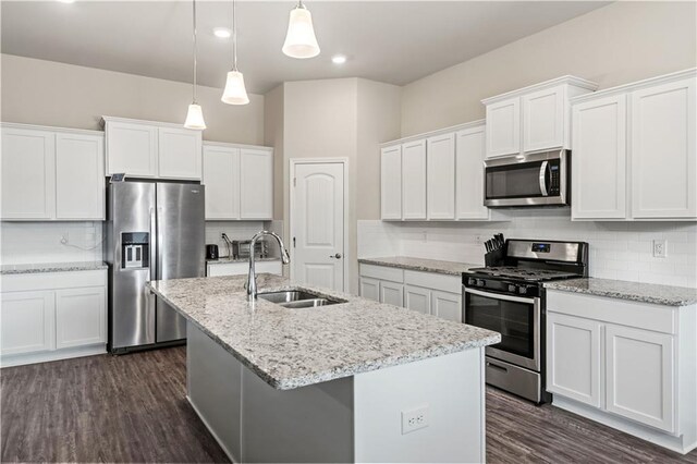 kitchen with stainless steel appliances, decorative light fixtures, a center island with sink, and white cabinets