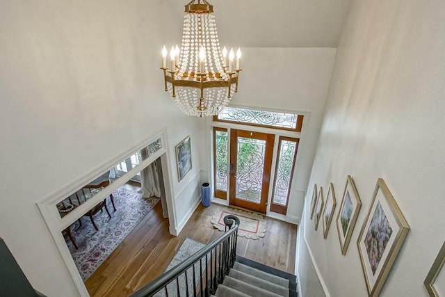 foyer with an inviting chandelier, a towering ceiling, and wood-type flooring