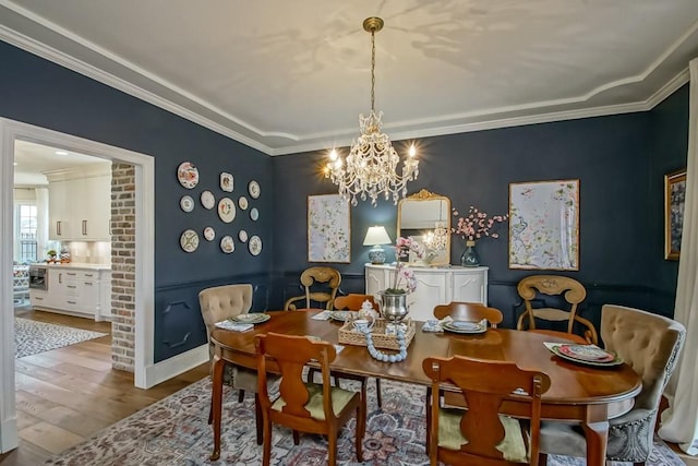 dining room with crown molding, wood-type flooring, and a chandelier