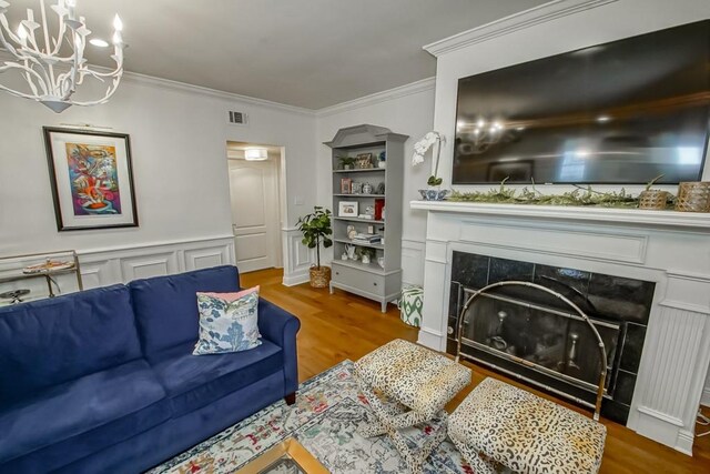 living room featuring hardwood / wood-style flooring, ornamental molding, and a tiled fireplace