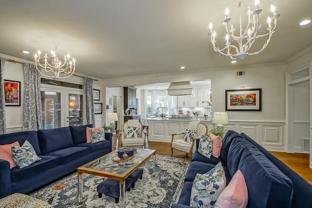 living room with an inviting chandelier, hardwood / wood-style flooring, and ornamental molding