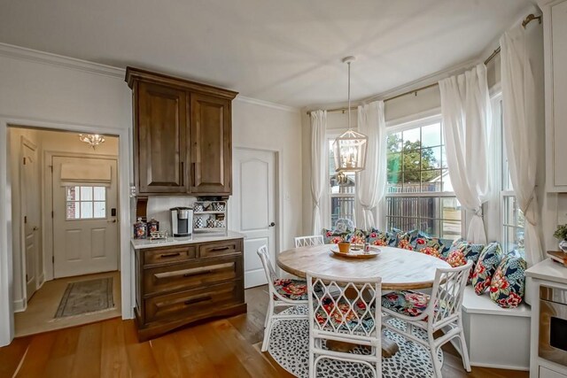 dining room with breakfast area, a notable chandelier, ornamental molding, and light wood-type flooring