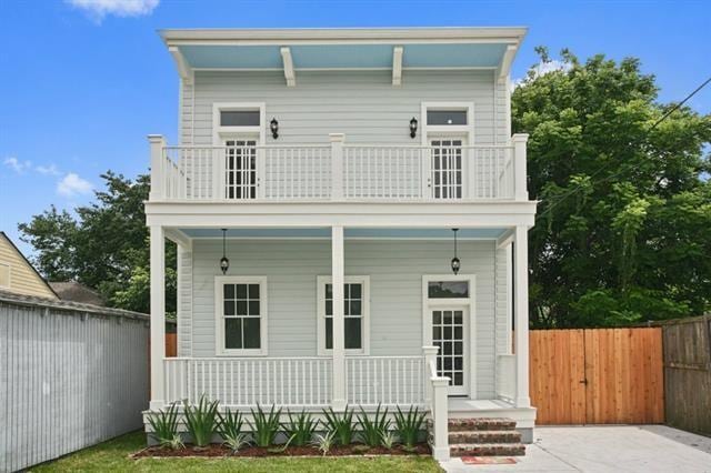 rear view of property with a balcony and a porch