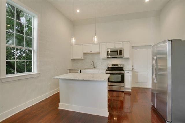 kitchen with stainless steel appliances, dark hardwood / wood-style floors, decorative backsplash, white cabinets, and decorative light fixtures