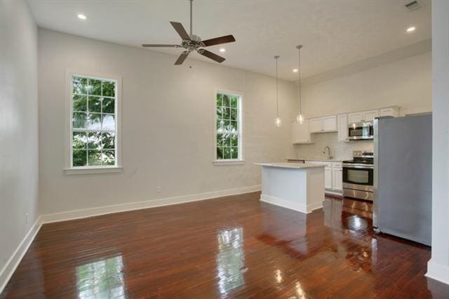 unfurnished living room with ceiling fan, plenty of natural light, sink, and dark hardwood / wood-style floors